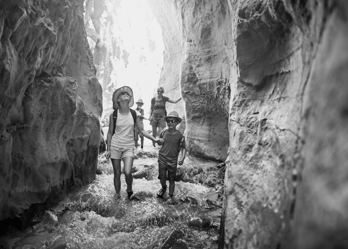 Mother and kids hiking through river Rio Chillar in Andalusia, Spain. They are walking in the mountain river flowing through the narrow canyon.